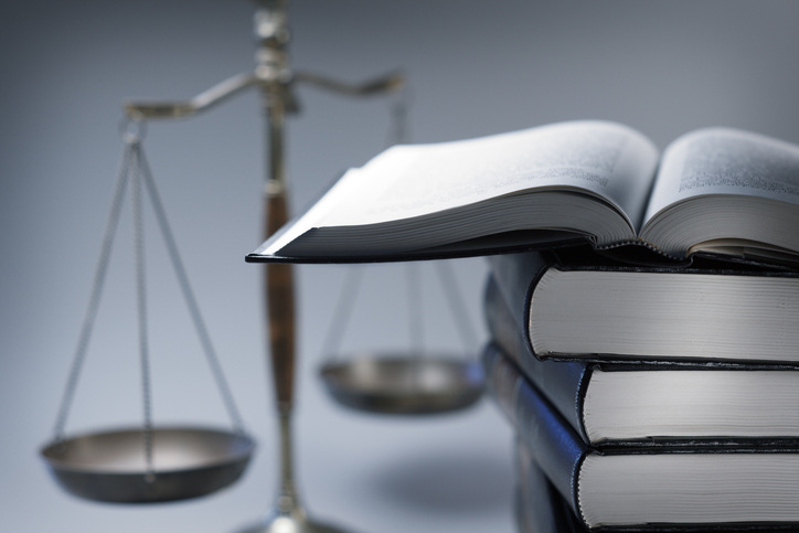 A stack of law books stands in front of a justice scale