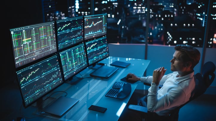 Financial Analyst Working on a Computer with Multi-Monitor Workstation with Real-Time Stock